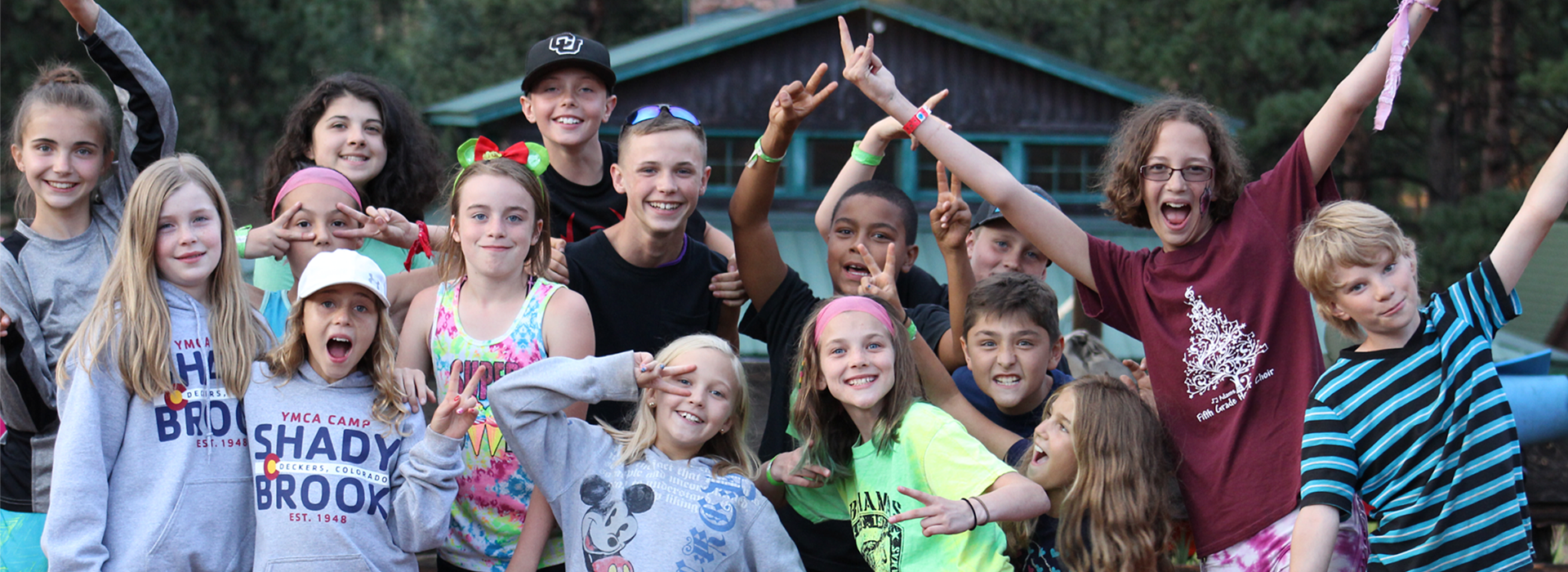 A large group of campers smiling and putting up peace signs