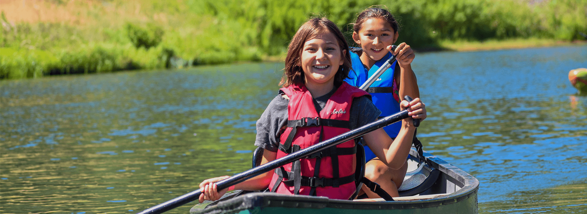 Two girls smiling in a canoe