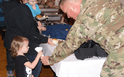 Military member helping serve food to a family